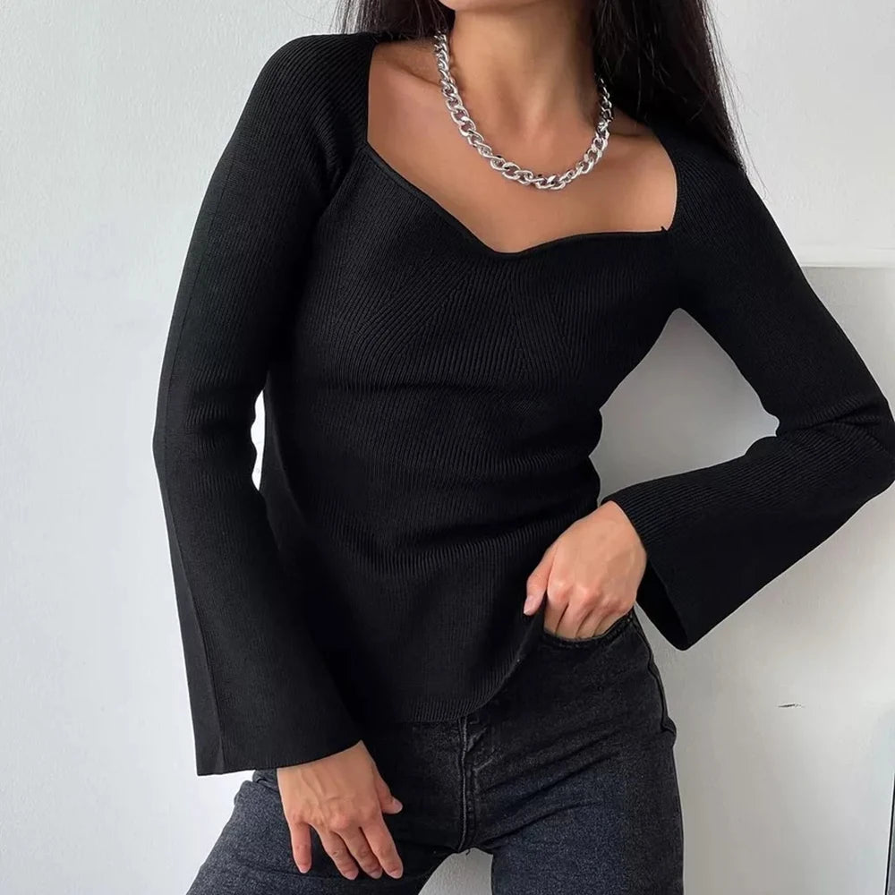 Model wearing black asymmetrical knit off shoulder sweater and dark jeans