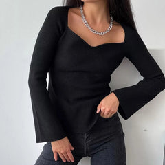 Model wearing black asymmetrical knit off shoulder sweater and dark jeans