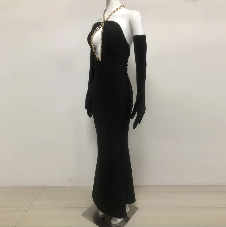 Mannequin wearing a black evening gown with gold accents on a plain background