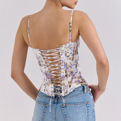 Woman wearing a floral lace-up top and blue jeans on a light gray background