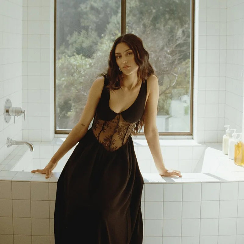 Woman in a black dress standing in a bathroom with large windows.