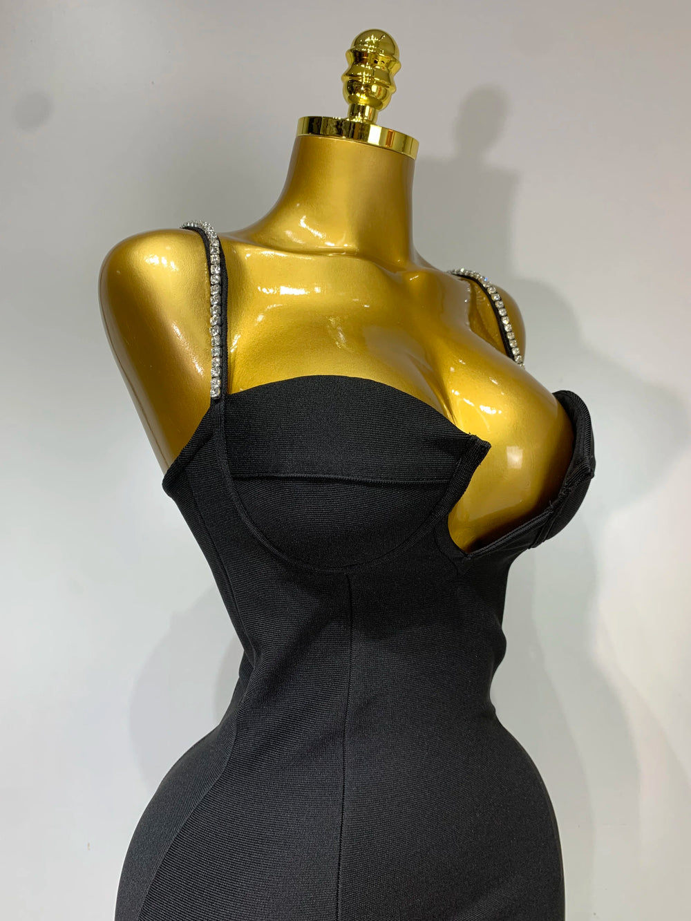 Black dress on a gold mannequin against a white background