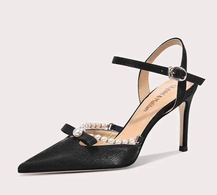 Black high-heeled shoe with pearl embellishments on a white background