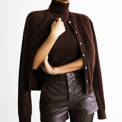 Person wearing a brown turtleneck sweater with a buttoned cardigan over a black leather outfit.