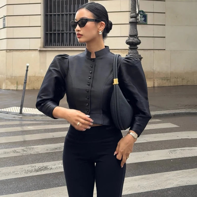 Woman in a black outfit standing on a city street