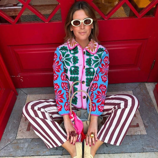 Model wearing a colorful floral print quilted jacket with blue and red floral accents.