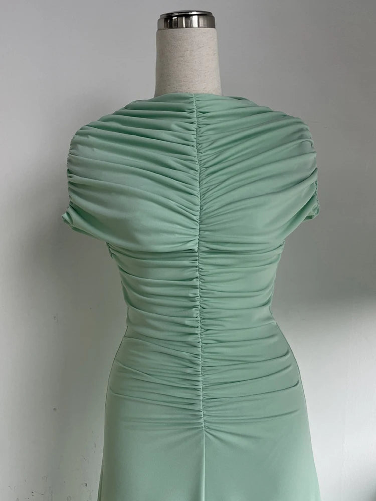 Green dress on a mannequin against a plain background