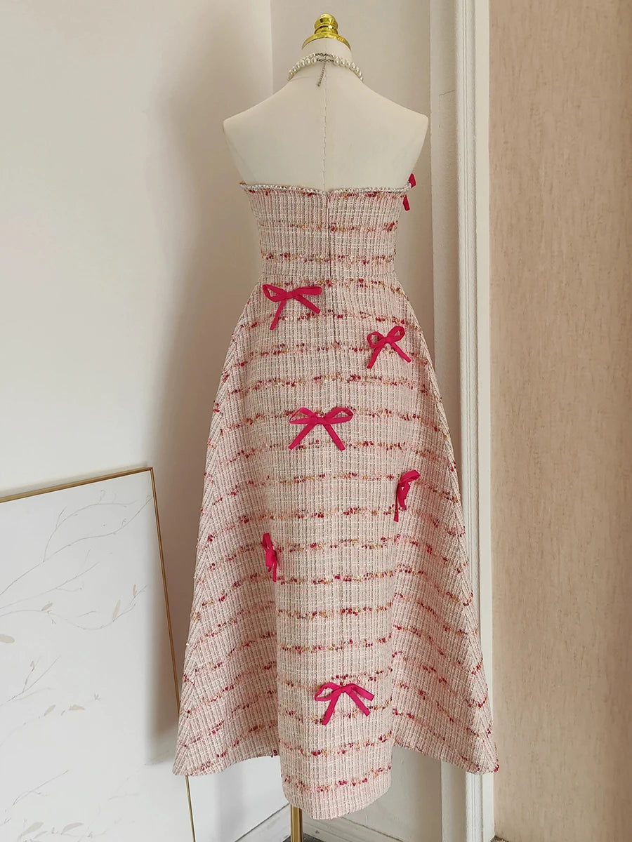 Strapless dress with red bow patterns on a mannequin against a neutral wall.