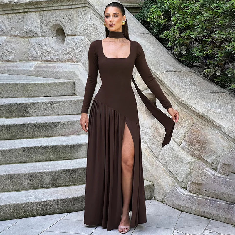 Woman in a brown long-sleeve dress with a slit standing on stone steps.