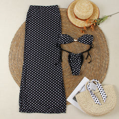 Flat lay of polka dot bikini, maxi skirt, straw hat, and beach bag