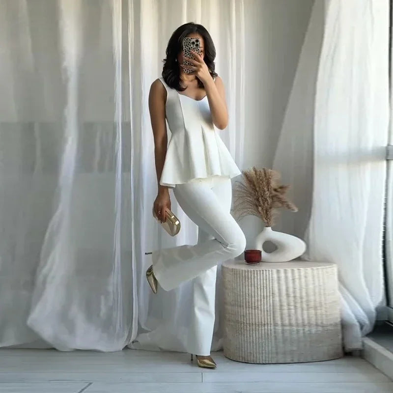 Woman in a white outfit posing in a room with white curtains and decor.