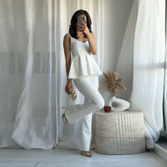 Woman in a white outfit posing in a room with white curtains and decor.