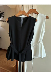 Black sleeveless top and white blouse on hangers against a neutral wall.