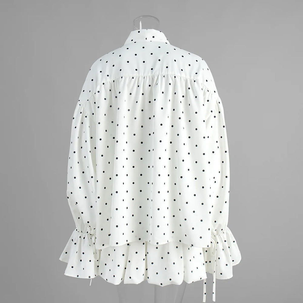 White blouse with black polka dots on a gray background