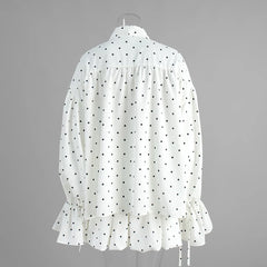 White blouse with black polka dots on a gray background