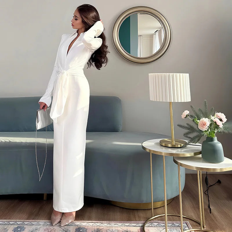 Woman in a white outfit standing in a modern living room with a blue sofa and decorative elements.