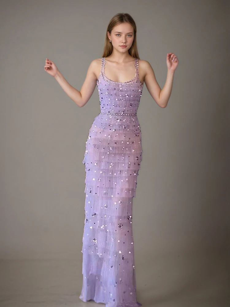 Woman wearing a lavender evening gown with beaded details against a plain background
