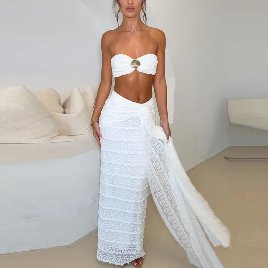 Woman wearing a white strapless top and wide-leg pants in a minimalistic room.