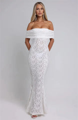 Woman wearing a white off-shoulder lace dress against a plain background