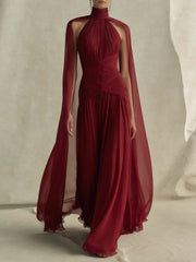Woman wearing a red halter neck cape sleeve maxi dress