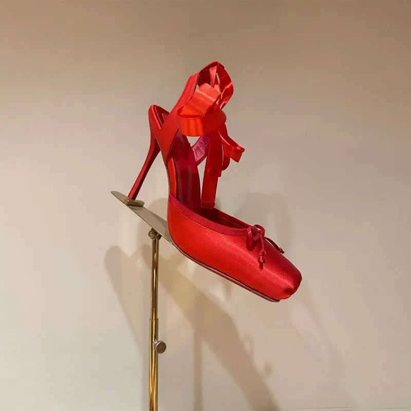 Red high-heeled shoes on a gold stand against a beige background