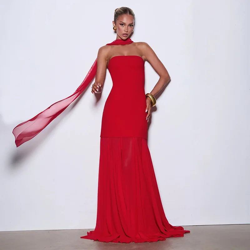 Woman wearing a red halter neck gown with a sheer overlay against a white background
