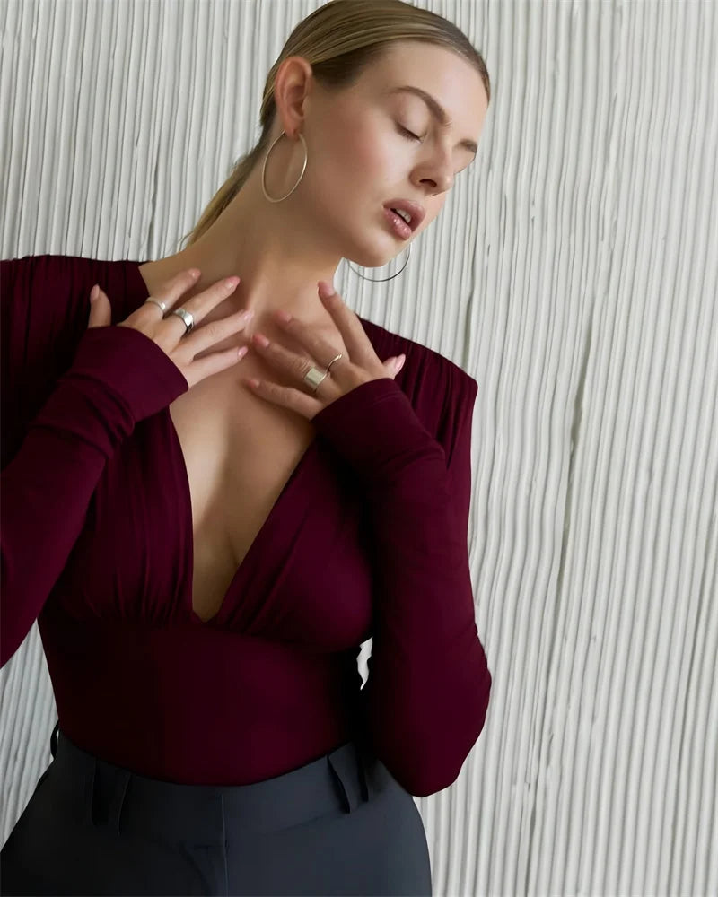 Woman wearing a burgundy top with a textured wall background