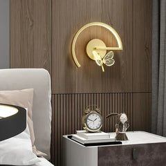 Modern wall sconce with butterfly design on a wooden wall above a nightstand.