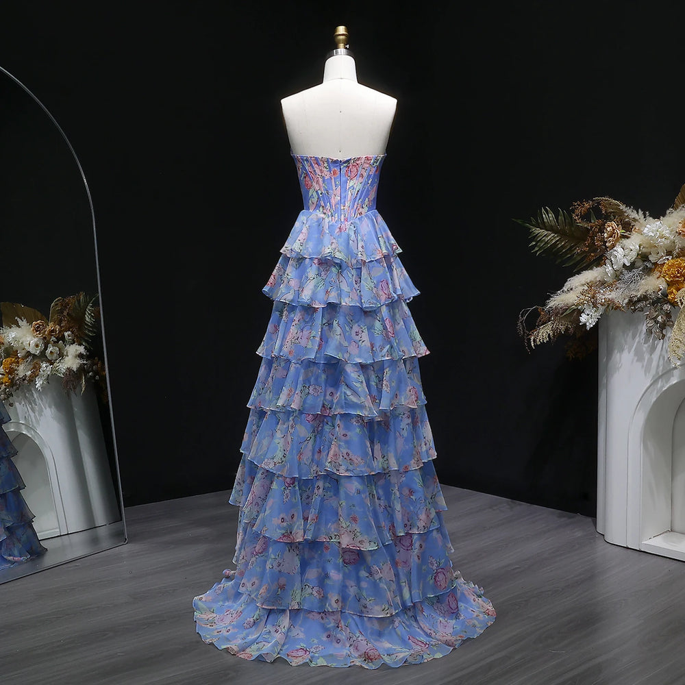 Blue floral tiered dress on a mannequin against a dark background with decorative elements.