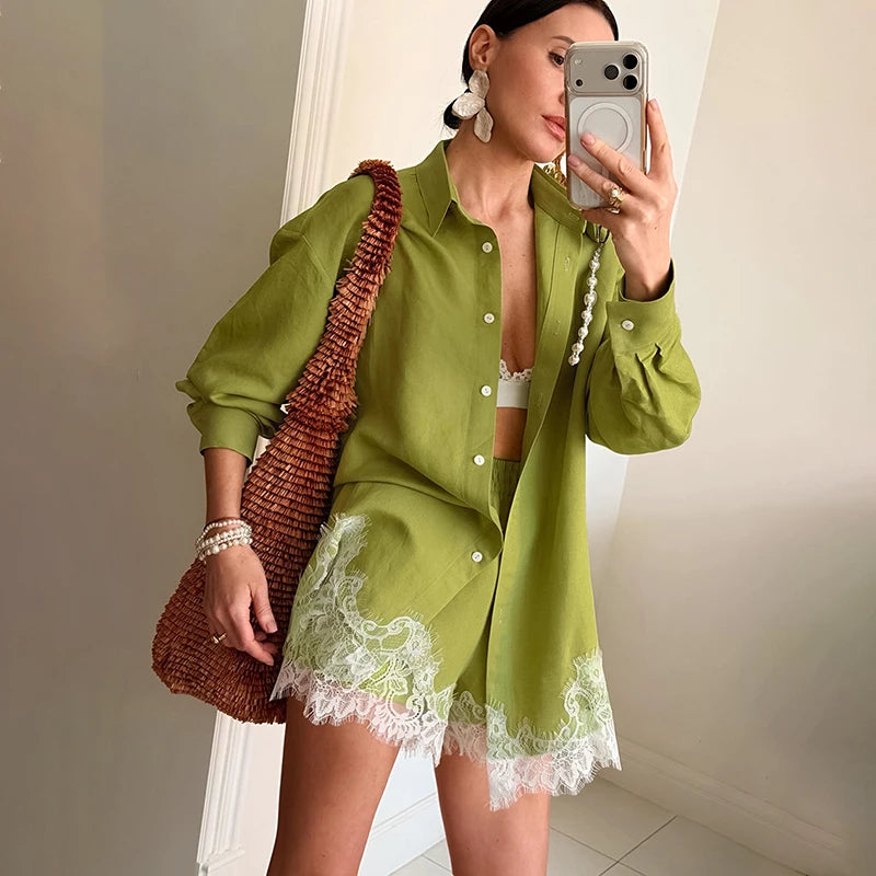 Woman taking a mirror selfie wearing a green outfit with lace details, holding a brown textured bag.