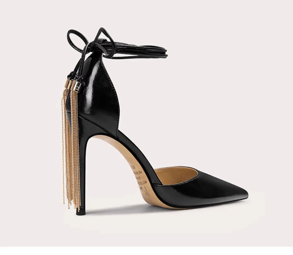 Black high-heeled shoe with gold accents on a light gray background