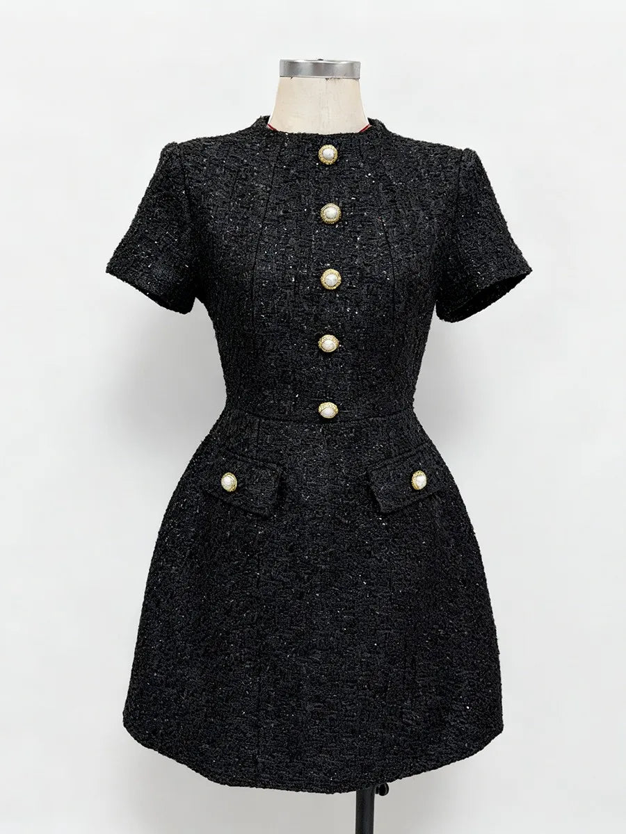 Black dress with pearl buttons on a mannequin against a white background