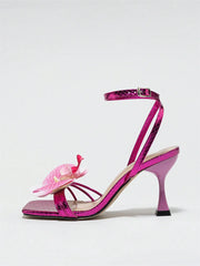 Pink high-heeled shoe with a decorative flower on a white background