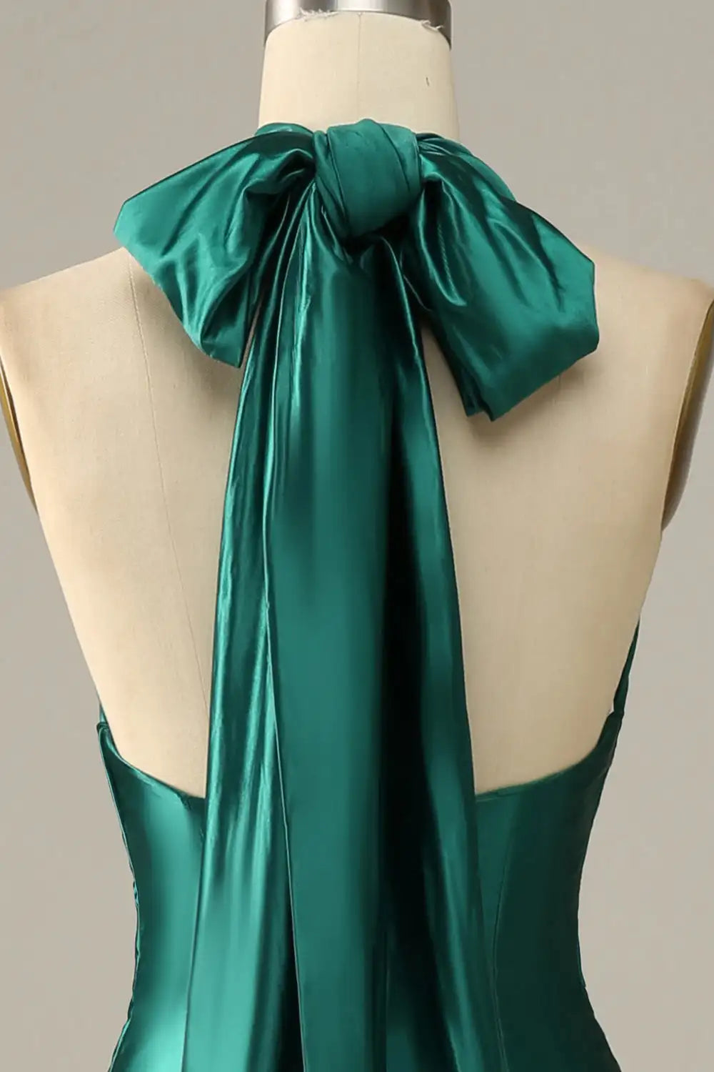 Teal satin dress on a mannequin with a bow detail against a neutral background