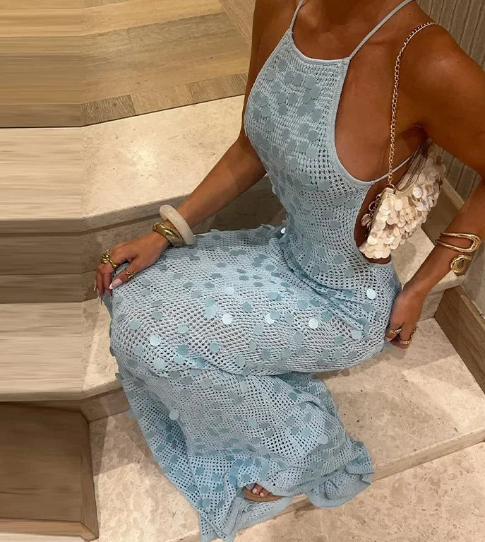 Woman wearing a light blue crochet dress sitting on a wooden bench.
