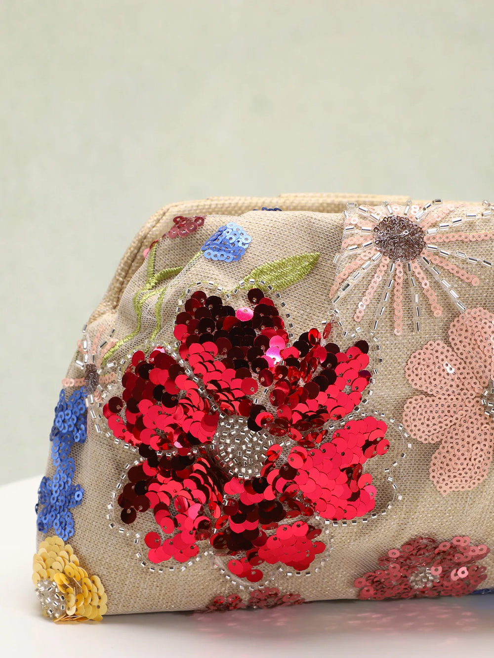 Embroidered clutch bag with floral patterns and sequins on a light background