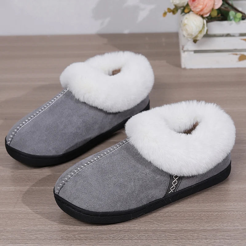 Gray slippers with white fuzzy fur lining on a wooden surface.
