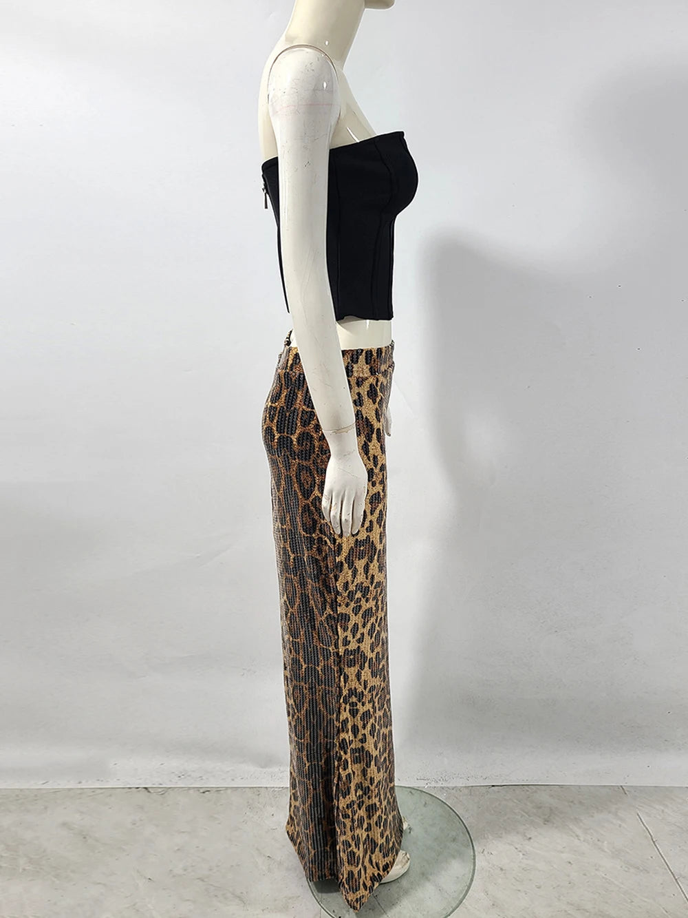 Mannequin wearing a black top and leopard print pants against a white background