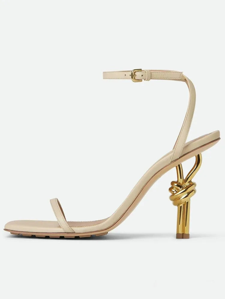 Beige sandal with gold knot design on a white background