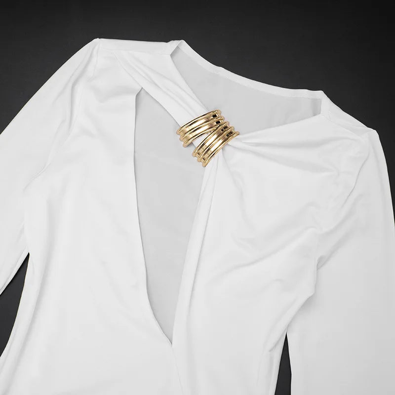 White garment with gold rings draped over it against a black background