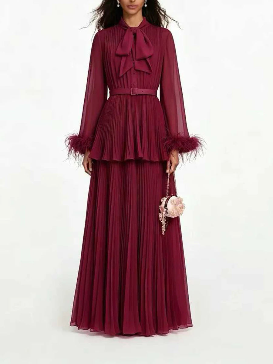 Burgundy pleated maxi dress with bow neck and feather trim