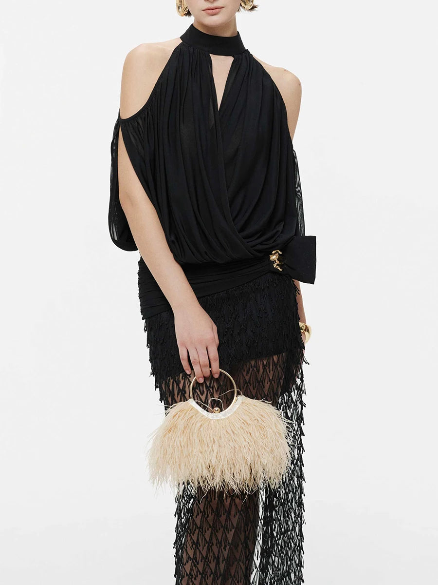 Model wearing black draped halter neck cold shoulder top with feather clutch