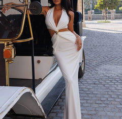 Woman in a white dress standing next to an old-fashioned vehicle on a cobblestone street.