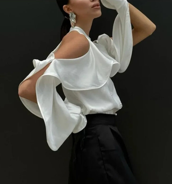 Woman wearing a white blouse with ruffled sleeves against a black background
