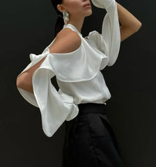 Woman wearing a white blouse with ruffled sleeves against a black background