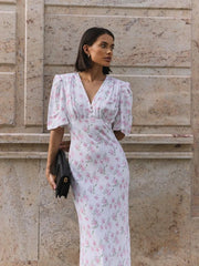 Woman wearing ankle-length white floral summer dress with V-neck and short sleeves.
