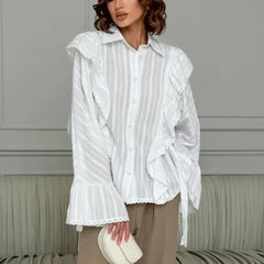 Woman wearing a white ruffled blouse against a neutral background