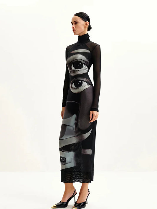 Model wearing a black dress with eye design on a white background