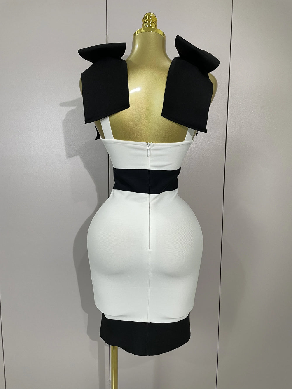 White dress with black accents on a mannequin against a plain background
