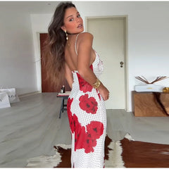 Woman wearing a white dress with red floral patterns in an indoor setting.